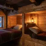 Chambre en bois avec deux lits et fenêtre enneigée