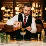 Bartender en costume versant un cocktail dans un verre élégant