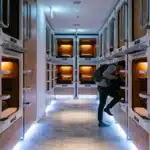 Personne dans couloir de capsules hôtel illuminées la nuit
