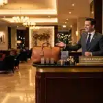 Réceptionniste accueillant client devant comptoir luxueux hôtel